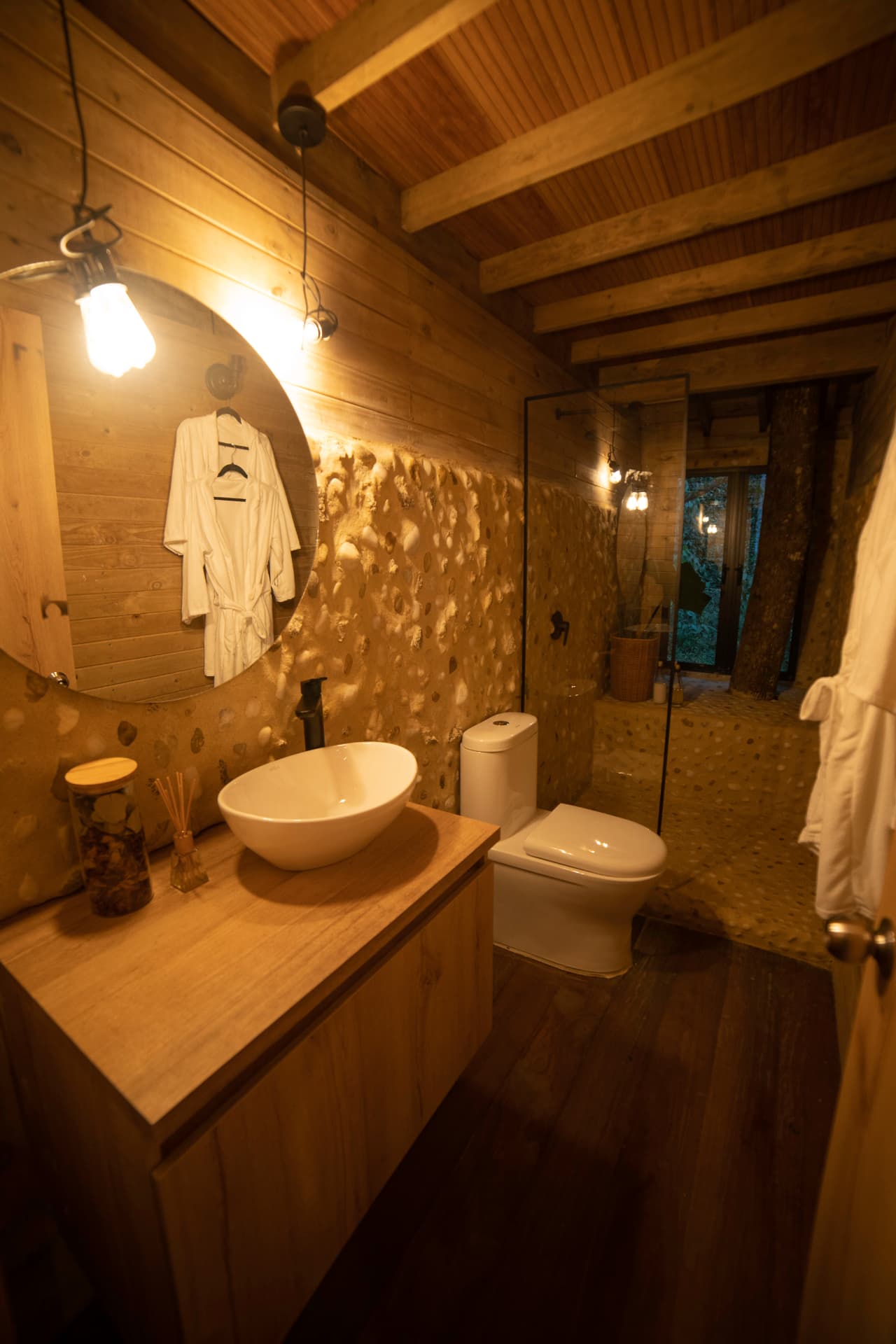 Baño en madera con lavamanos, espejo circular y ducha