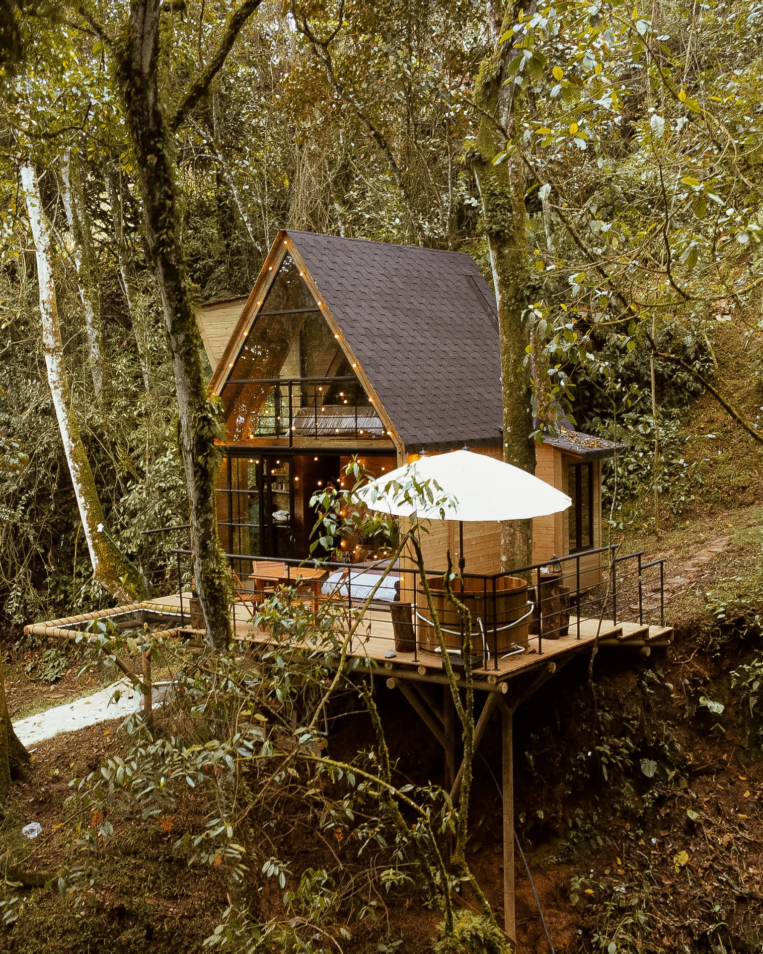 Deck de la cabaña Cedro con ofuro bajo sombrilla y zona de hamaca rodeada de árboles