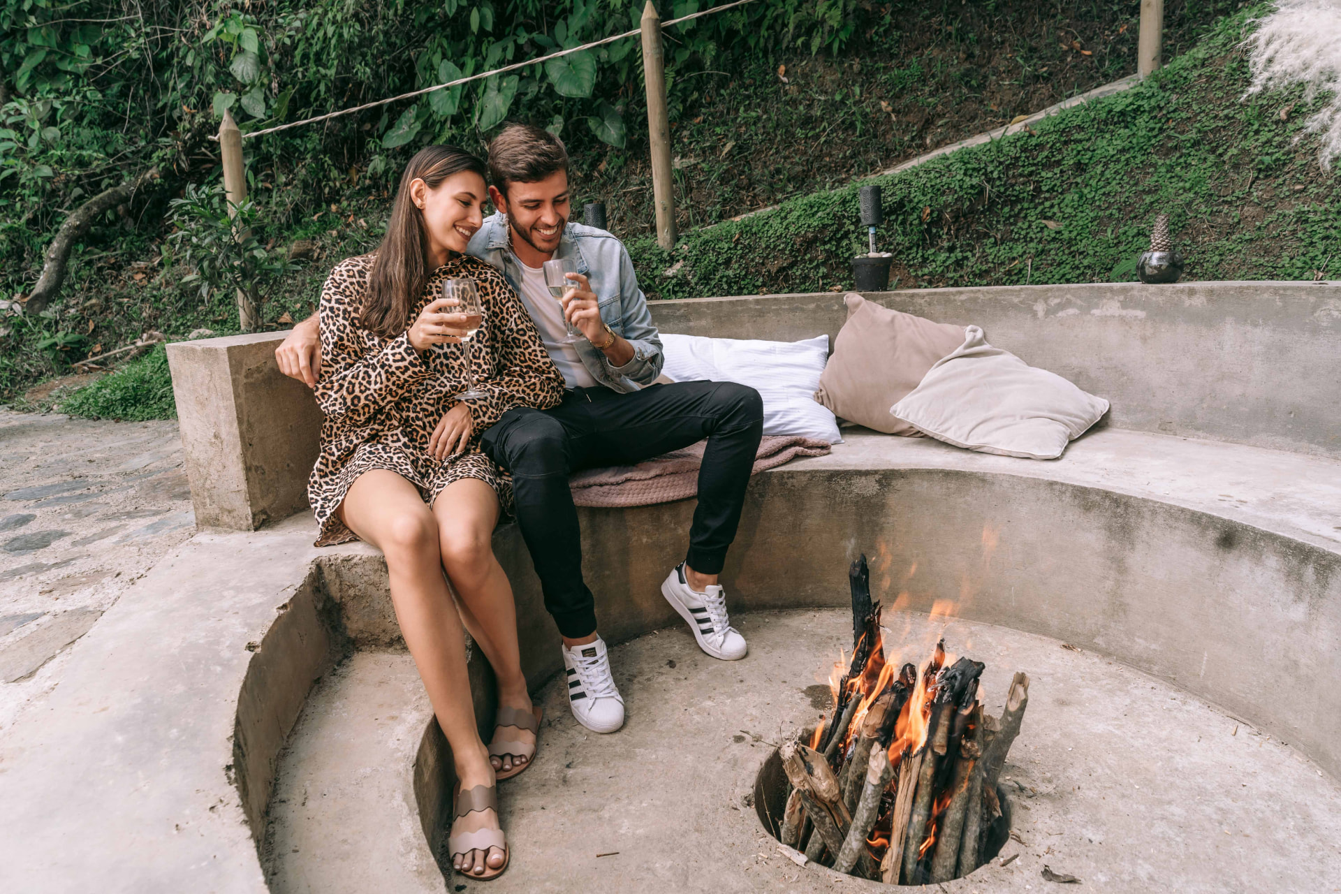 Pareja brindando con vino junto a la fogata en el exterior de la cabaña Cedro